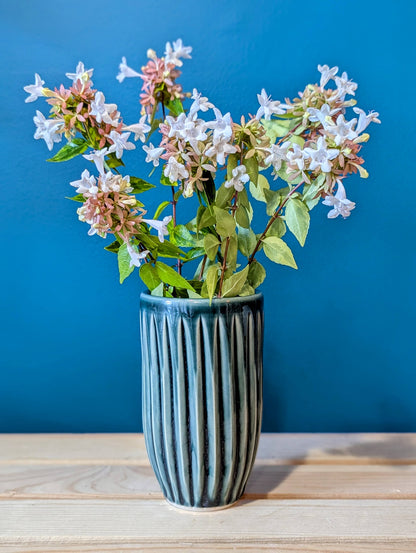 Vase with flowers against a blue wall